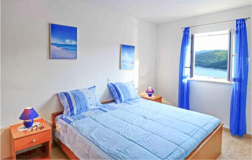 a bedroom with a blue bed and a window at Beautiful Home In Rabac With House Sea View in Rabac