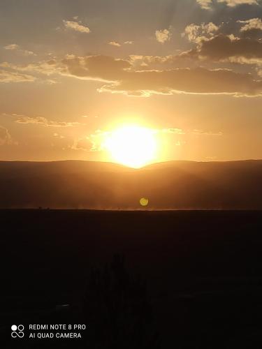 una puesta de sol sobre un campo con el sol en el cielo en Cabañas PAIGÜEN, en Villa Yacanto