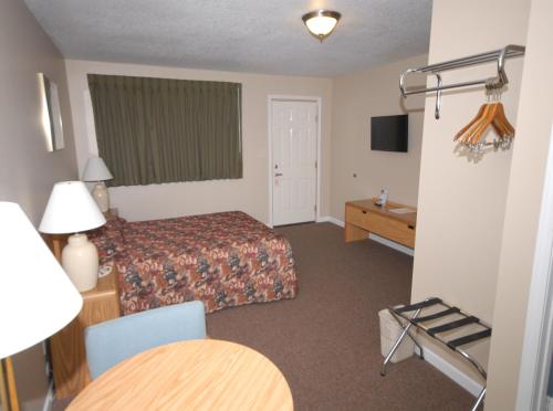 a hotel room with a bed and a table at Wayside Motel in Saint Ignace