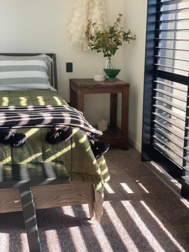 a bedroom with a bed and a table and a window at Napier Apartment Ahuriri in Napier