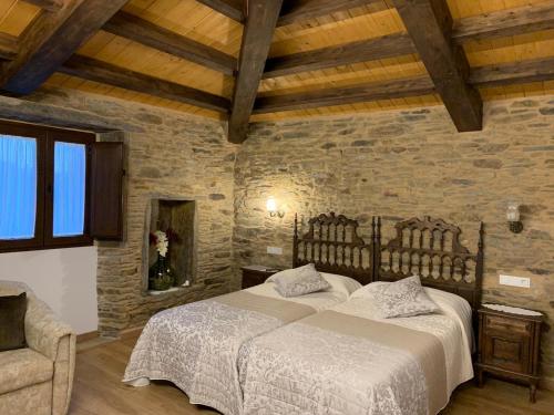 a bedroom with a bed and a stone wall at Casa do Horreo in O Pino 