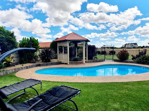 a swimming pool with a gazebo and a bench at Werribee Park Motor Inn in Werribee