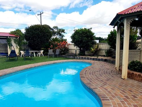 a swimming pool with a brick walkway next to a house at Werribee Park Motor Inn in Werribee
