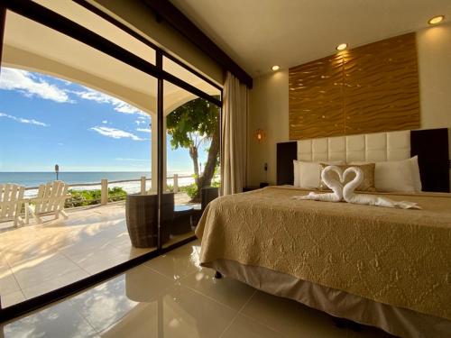 a bedroom with a bed and a view of the ocean at Vista Las Olas Resort in El Cuco