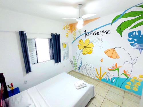 - une chambre avec un lit orné d'une fresque murale représentant des fleurs dans l'établissement Casa Mar Peruíbe, à Peruíbe