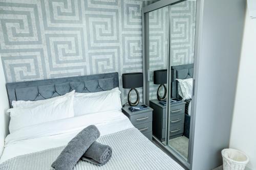 1 dormitorio con cama y espejo grande en Attractive 2 Bedroom Penthouse with free Parking, en Romford