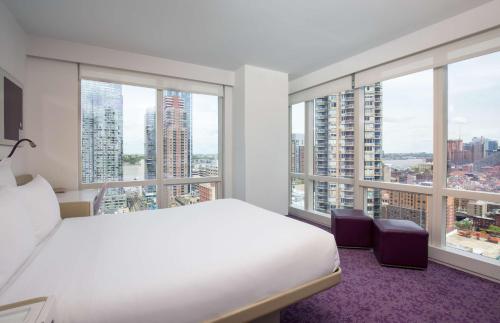 a bedroom with a white bed and large windows at YOTEL New York Times Square in New York