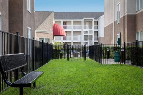 a park bench next to a fence with a building at Sonesta ES Suites Dallas Medical Market Center in Dallas