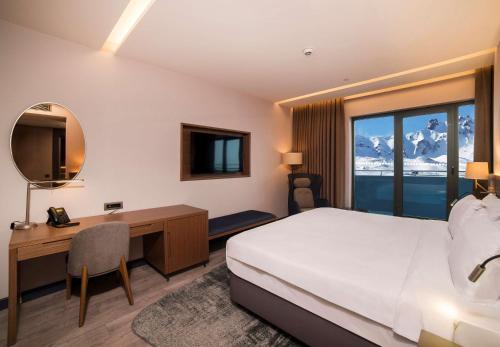 ErciyesにあるRadisson Blu Hotel, Mount Erciyesのベッド、デスク、窓が備わるホテルルームです。
