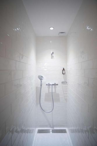 a white bathroom with a shower with a hose at Les Demeures de Varennes, BW Signature Collection in Varennes-Jarcy