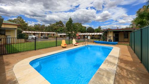 una piscina en un patio con 2 sillas amarillas en Golden Peak Motel PeakHill, en Peak Hill