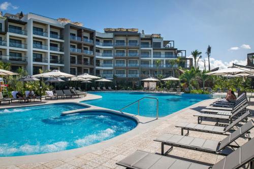a swimming pool with chairs and a hotel at Ventus Ha at Marina El Cid Spa & Beach Resort - All Inclusive in Puerto Morelos