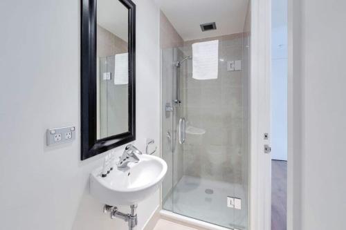 ein Bad mit einem Waschbecken und einer Dusche mit einem Spiegel in der Unterkunft THE VIADUCT WATERFRONT LUXURY - Views & Location! in Auckland