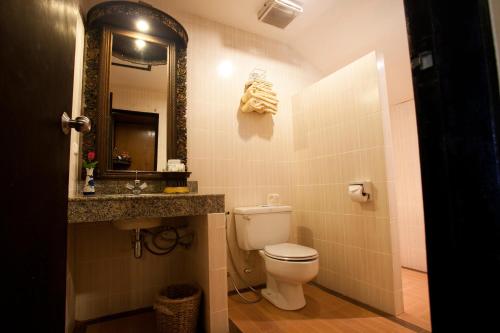 a bathroom with a toilet and a sink and a mirror at Lampang River Lodge - SHA certified in Lampang