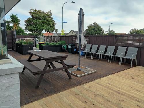 a wooden deck with a picnic table and chairs and an umbrella at Holiday Home in Papamoa in Tauranga