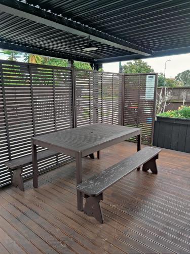 a picnic table and benches on a wooden deck at Holiday Home in Papamoa in Tauranga