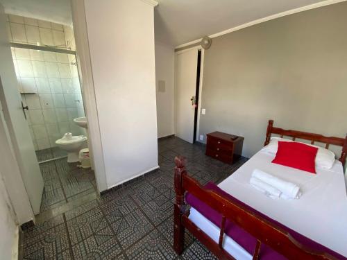 a bedroom with a bed and a bathroom with a toilet at Hotel dos Nobres in Poços de Caldas