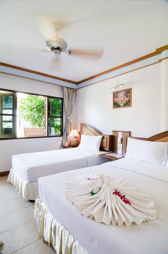 two beds in a room with white walls at Sea Garden Resort & Spa, Haadrin in Haad Rin