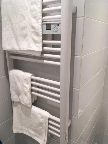 un baño con toallas blancas en un toallero. en Résidence Oceanica, en Bourbonne-les-Bains