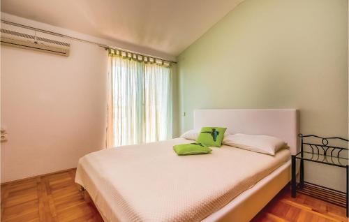 Amazing Apartment In Dramalj With House Sea View في دْرامالج: غرفة نوم عليها سرير ووسادتين خضراء