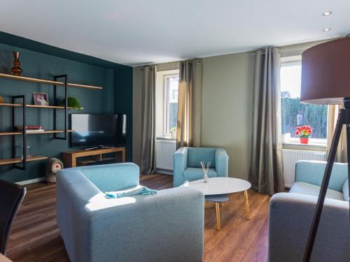 a living room with blue chairs and a tv at Cozy holiday home in Lemberg in Lemberg