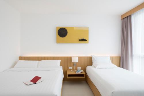 a hotel room with two beds and a book on a table at Modern Thai Suites in Phuket Town