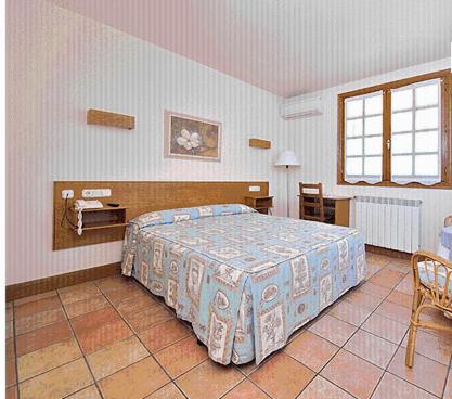 1 dormitorio con 1 cama, mesa y sillas en Hostal Lorentxo, en Olave