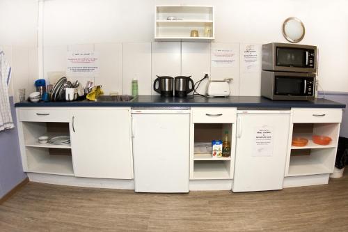 a kitchen with white cabinets and a microwave and a counter at Happy Inn Lodge in Interlaken