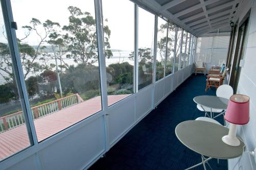 a balcony with tables and chairs and windows at 970 Adventure Bay Road in Adventure Bay