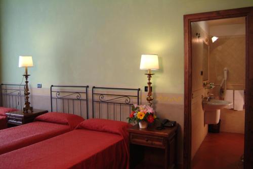 a bedroom with two red beds and a sink at Domus Sessoriana in Rome