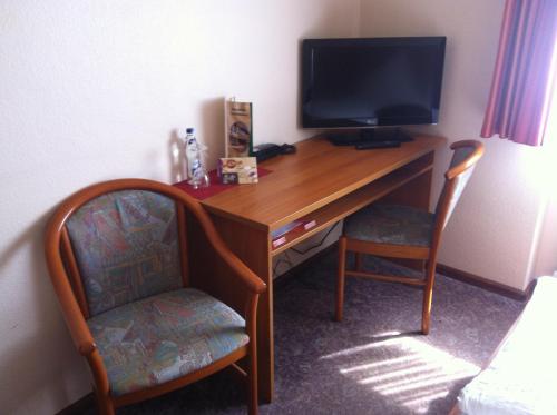 a desk with a television and a chair in a room at Hotel Ochsen Kehl-Kork in Kehl am Rhein