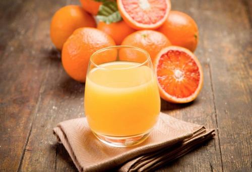 a glass of orange juice next to a pile of oranges at The Railroad Inn in Cooperstown