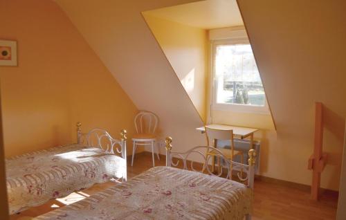 a attic room with two beds and a window at Nice Home In Guehenno With 3 Bedrooms And Wifi in Guéhenno