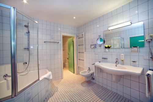 a bathroom with a tub and a sink and a shower at Stadthotel Freiburg Kolping Hotels & Resorts in Freiburg im Breisgau