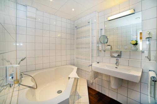 a white bathroom with a tub and a sink at Stadthotel Freiburg Kolping Hotels & Resorts in Freiburg im Breisgau