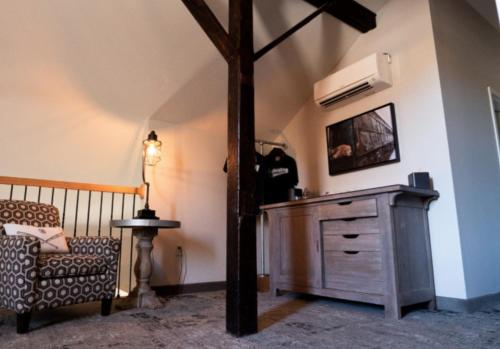 a room with a chair and a dresser and a television at The Railroad Inn in Cooperstown