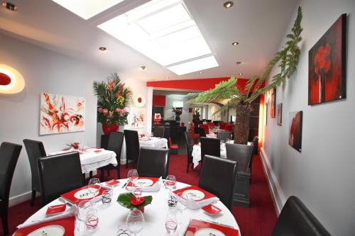 une salle à manger avec des tables blanches et des chaises noires dans l'établissement Auberge bretonne, à Châteaubriant