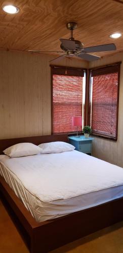 a bedroom with a large bed with a ceiling fan at Seven Bluff Cabins in Concan