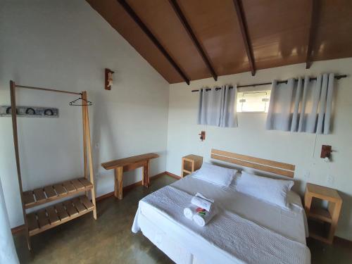 a bedroom with a large bed and a table at Pousada Terraço Guarapari in Guarapari