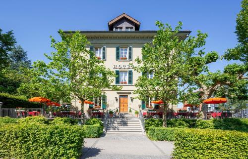 a white building with orange umbrellas in front of it at Hotel Landgasthof Schönbühl in Schönbühl