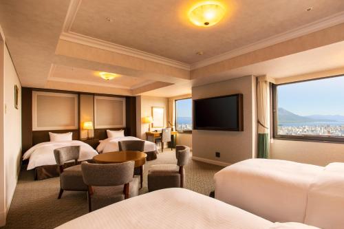 a hotel room with four beds and a flat screen tv at SHIROYAMA HOTEL kagoshima in Kagoshima