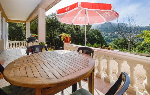 d'une table en bois avec des chaises et un parasol sur le balcon. dans l'établissement Villa Nicolas, à Coti-Chiavari