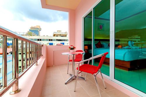 a balcony with two chairs and a table and a bed at Phusita Hotel - SHA Certified in Patong Beach