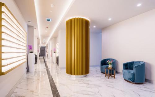 Un pasillo con dos sillas azules y una gran columna amarilla. en ORBI CITY Hotel Sea View, en Batumi