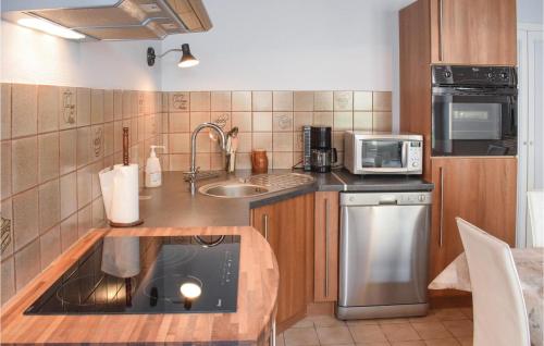 une petite cuisine avec un évier et un micro-ondes dans l'établissement Pet Friendly Home In Sainte-Mère-Eglise, à Sainte-Mère-Église