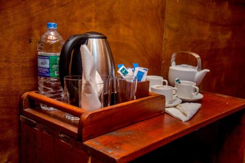 a wooden tray with a tea kettle and cups on a table at Sinharaja Forest Gate in Deniyaya