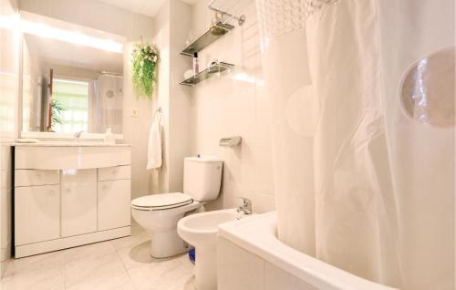 a white bathroom with a toilet and a bath tub at 4 Bedroom Beautiful Home In Santa Susanna in Santa Susanna