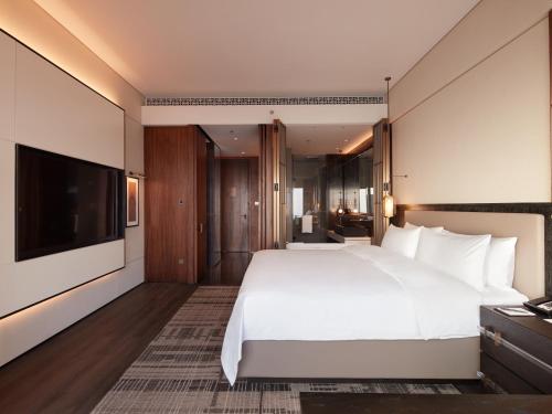 a bedroom with a large white bed and a flat screen tv at Shangri-La Nanning - The tallest hotel worldwide in Shangri-La Group in Nanning
