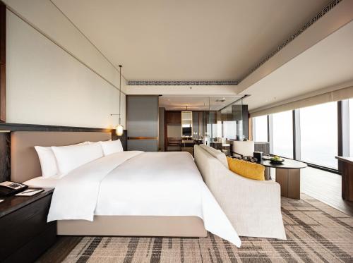 a bedroom with a large white bed and a living room at Shangri-La Nanning - The tallest hotel worldwide in Shangri-La Group in Nanning