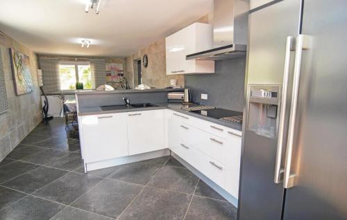 une cuisine avec des armoires blanches et un réfrigérateur en acier inoxydable dans l'établissement Nice Home In Le Grau D'agde, au Grau-dʼAgde